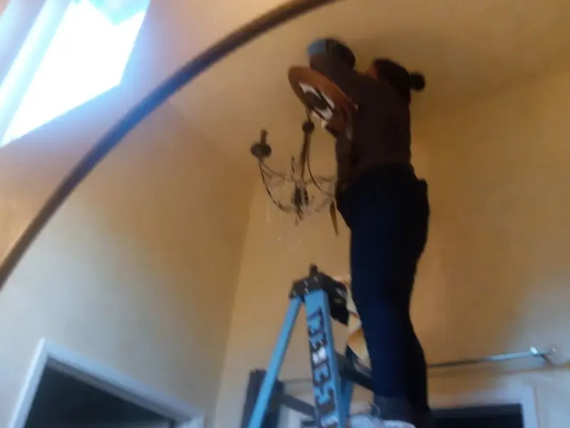 Electrician installing a chandelier in a Sharpsville residence
